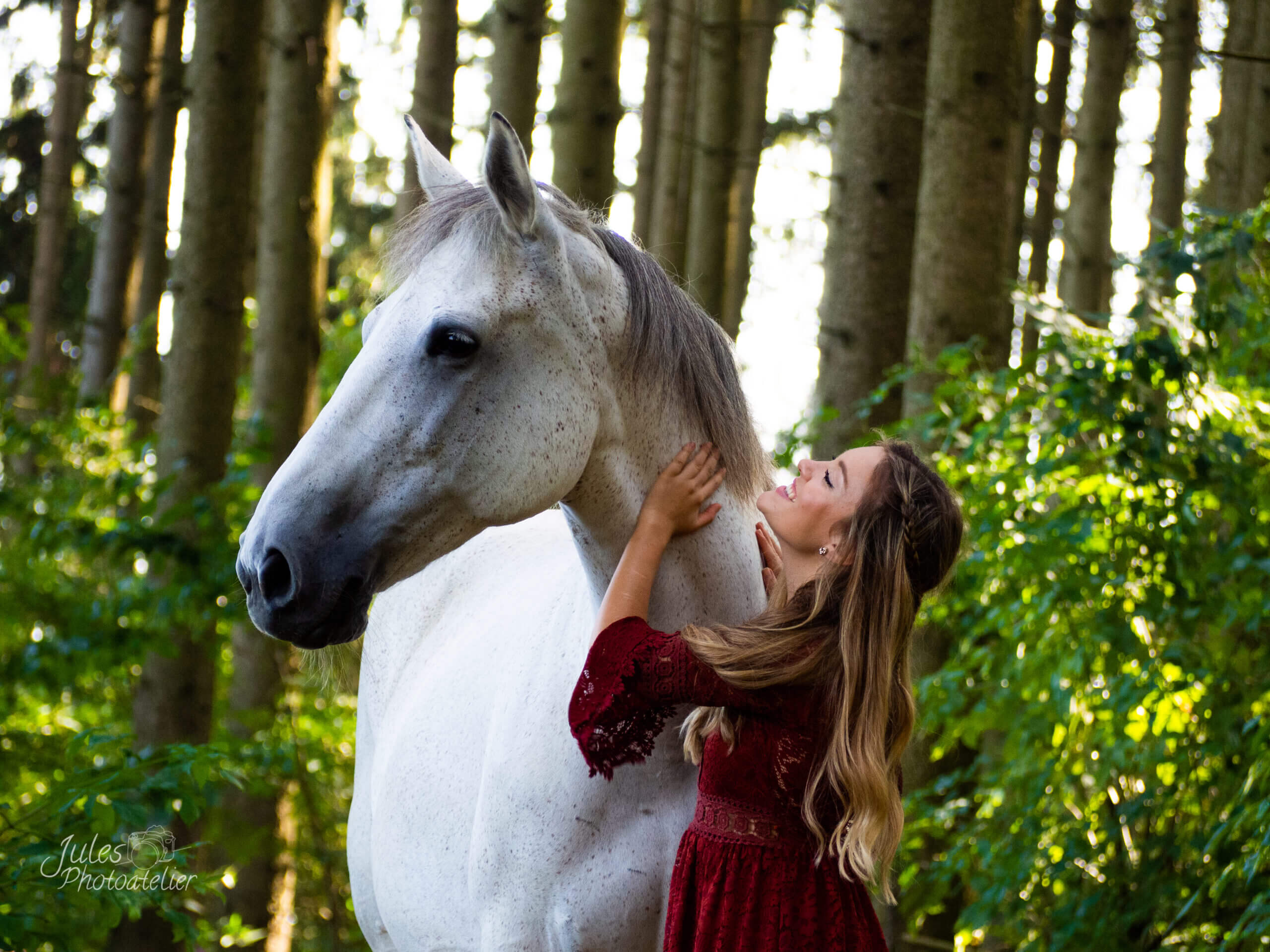 glückliches Mädchen mittelalterlich gekleidet mit Schimmel Stute ohne Halfter kuschelnd bei Fotoshooting mit Fellnasen